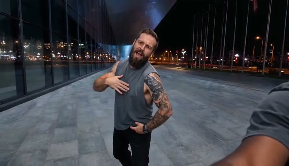 The bearded man taking the chest-and-hip solo on the plaza in a Gangnam Style AI sample video, one hand on the chest and one on the hip